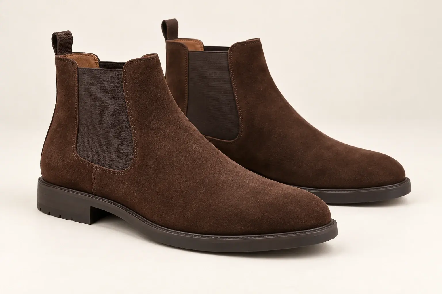 Illustration par IA de bottines Chelsea en daim marron sans marque, avec empiècements latéraux élastiques et sans lacets.